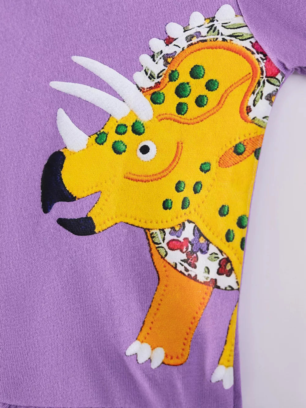 Toddler purple cotton crew neck dress with yellow dinosaur applique and floral accents.