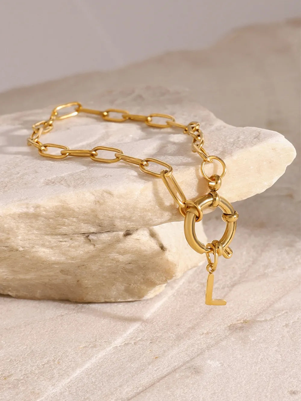 Gold chunky chain bracelet with a toggle clasp and an initial L charm.