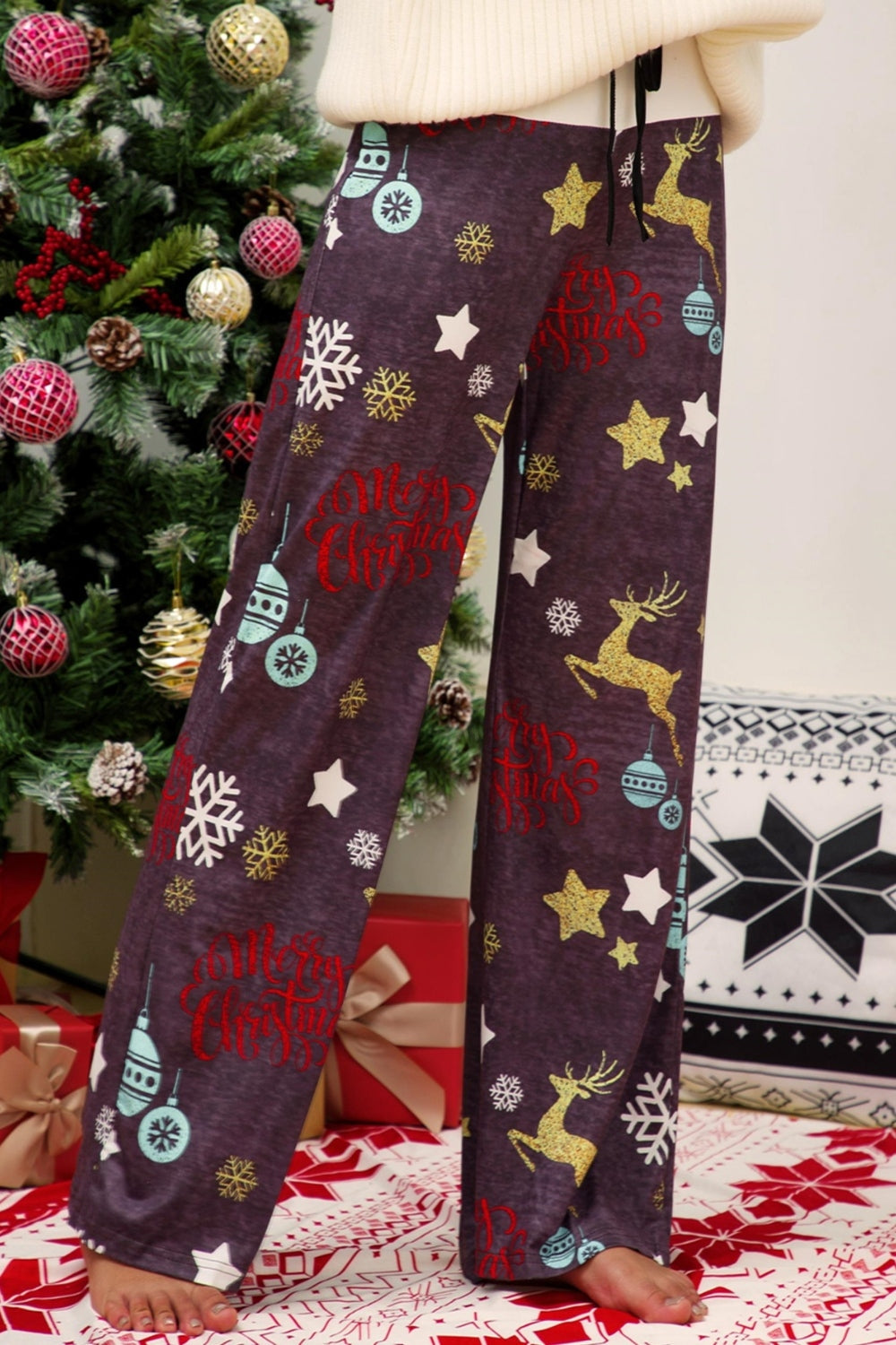 Festive print wide-leg lounge trousers in dusty purple with Christmas motifs like reindeer, snowflakes, and ornaments.