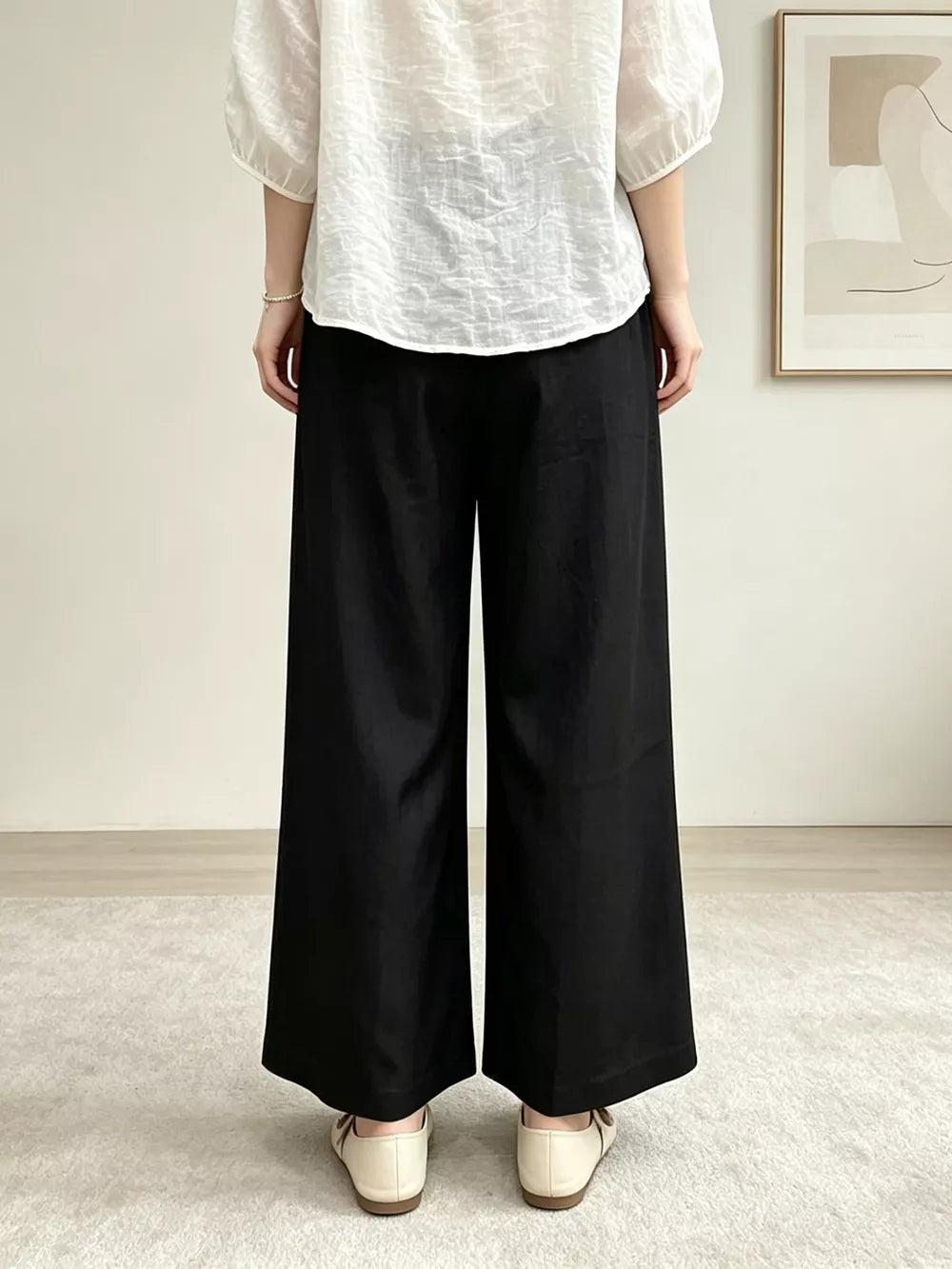 Black maternity pants with pockets and a wide leg, shown from the back.