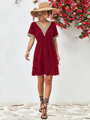 Burgundy A-line dress with Swiss dots, V-neck, crochet trim, and ruffled hem.