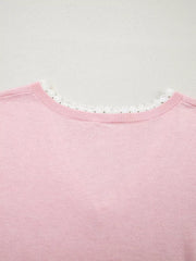 Pink knit top with delicate white lace trim at the V-neckline.