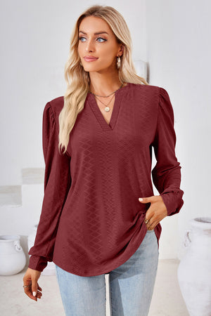 Burgundy textured blouse with bishop sleeves and a v-neckline.