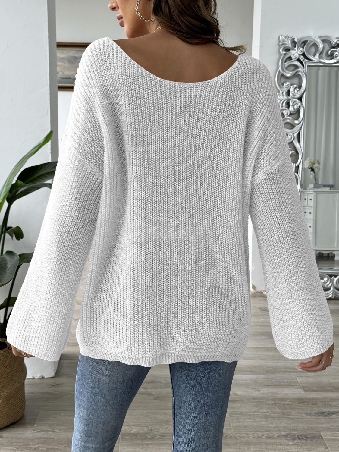 White slouchy boatneck knit sweater with wide sleeves and ribbed texture.