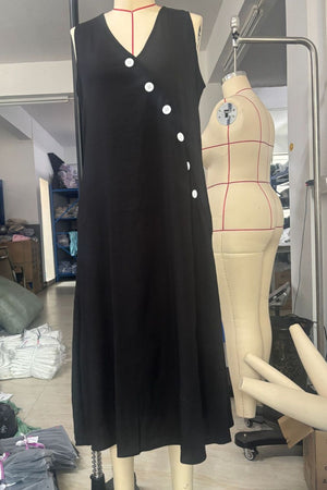 Black asymmetrical button-down midi dress with V-neck and sleeveless cut.