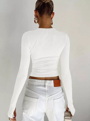 White long sleeve t-shirt with ruching detail and thumbholes, styled with white jeans.