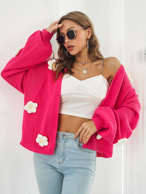Hot pink knit cardigan with balloon sleeves and floral appliqués.