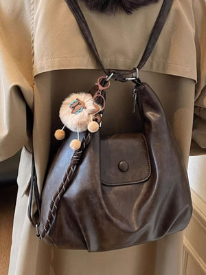 Vintage pu leather shoulder bag in olive brown with a fluffy sheep charm and braided strap detail.