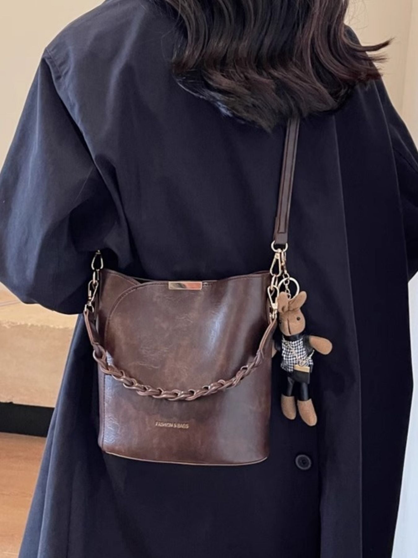 Brown braided bucket crossbody bag with chain strap and plush bunny charm