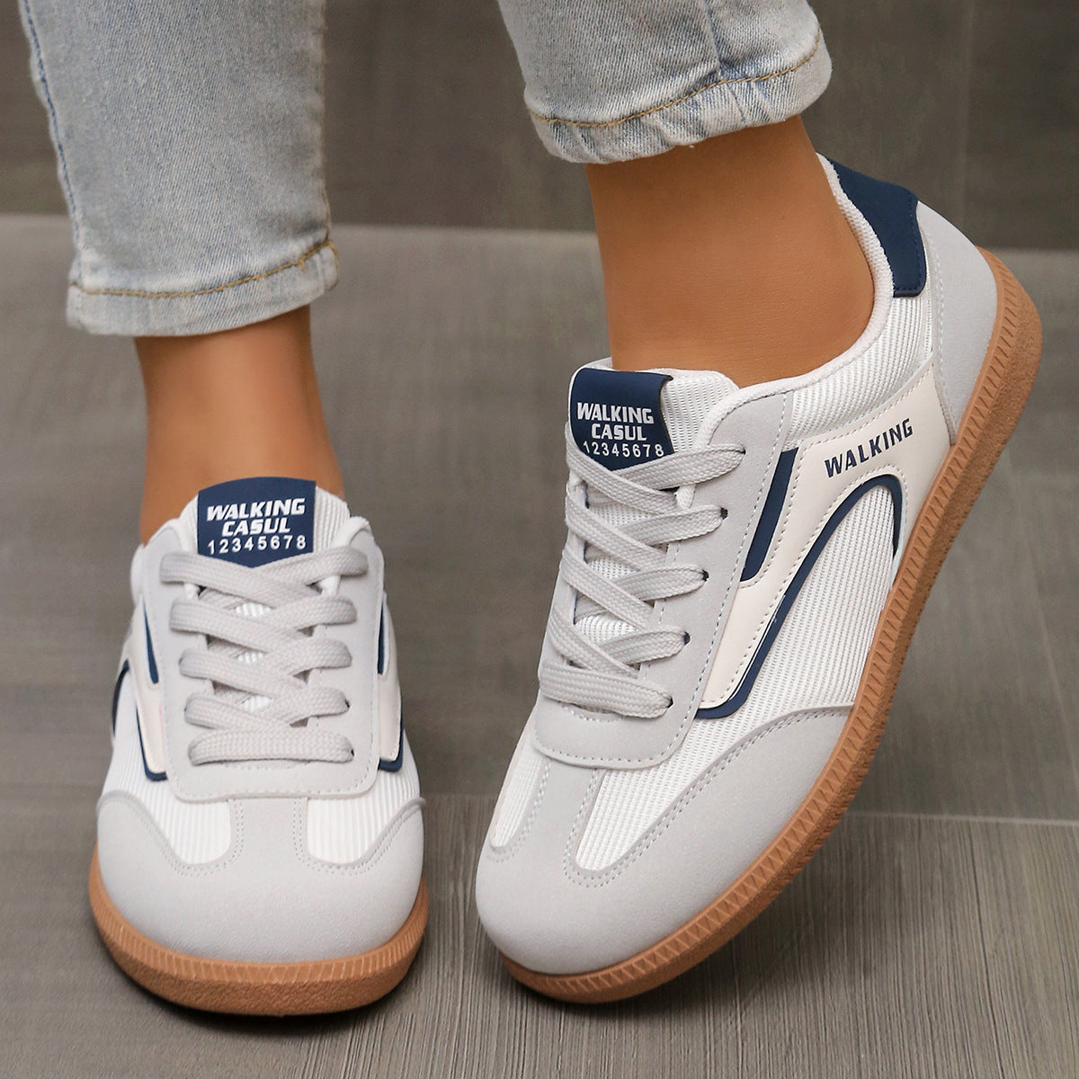 White and grey lace-up sneakers with blue accents and gum soles.