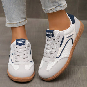 White and grey lace-up sneakers with blue accents and gum soles.