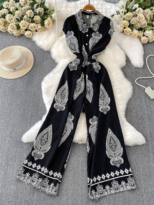Black wide leg romper with white paisley print, collared, button-down, short sleeves.