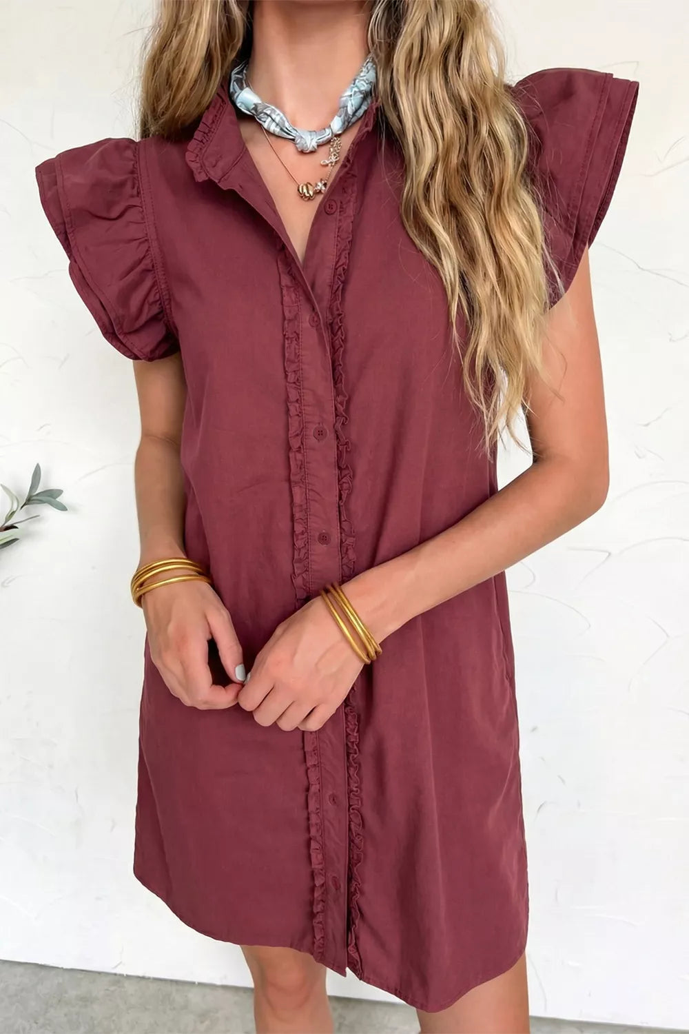Burgundy denim button-down mini dress with ruffled trim and flutter sleeves.