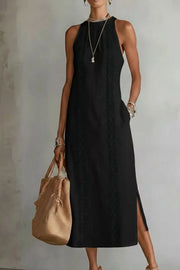 Black midi dress with pockets, sleeveless, high neck, and side slits.