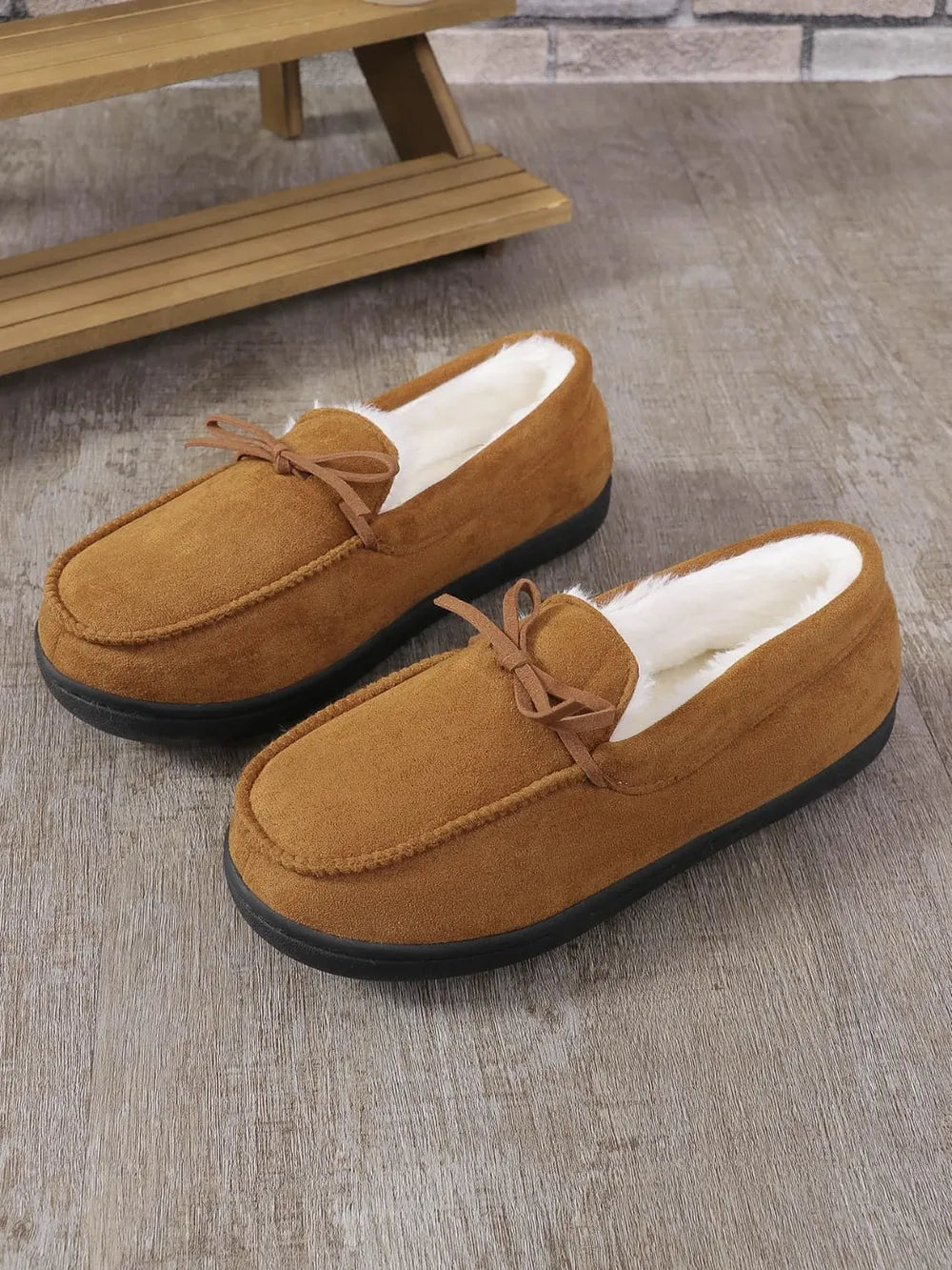 Caramel suede moccasin slippers with white faux fur lining and bow detail.