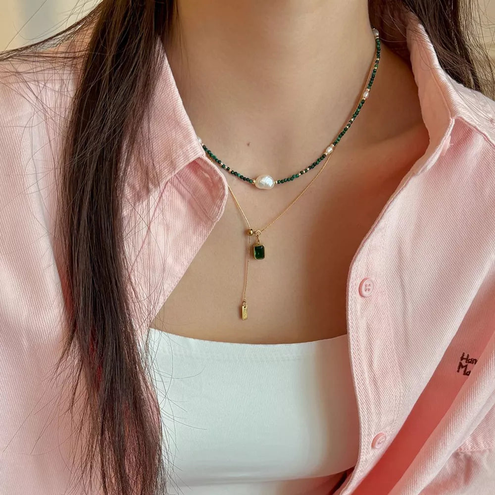 Elegant freshwater pearl and malachite beaded necklace with a gold chain and emerald pendant.