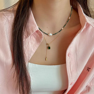 Elegant freshwater pearl and malachite beaded necklace with a gold chain and emerald pendant.