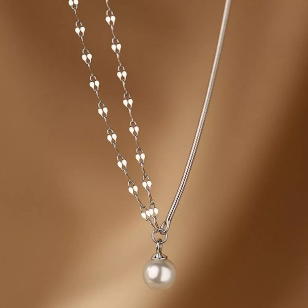 Sterling silver layered necklace with a single pearl pendant and delicate heart-shaped chain.
