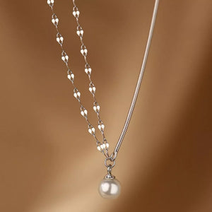 Sterling silver layered necklace with a single pearl pendant and delicate heart-shaped chain.