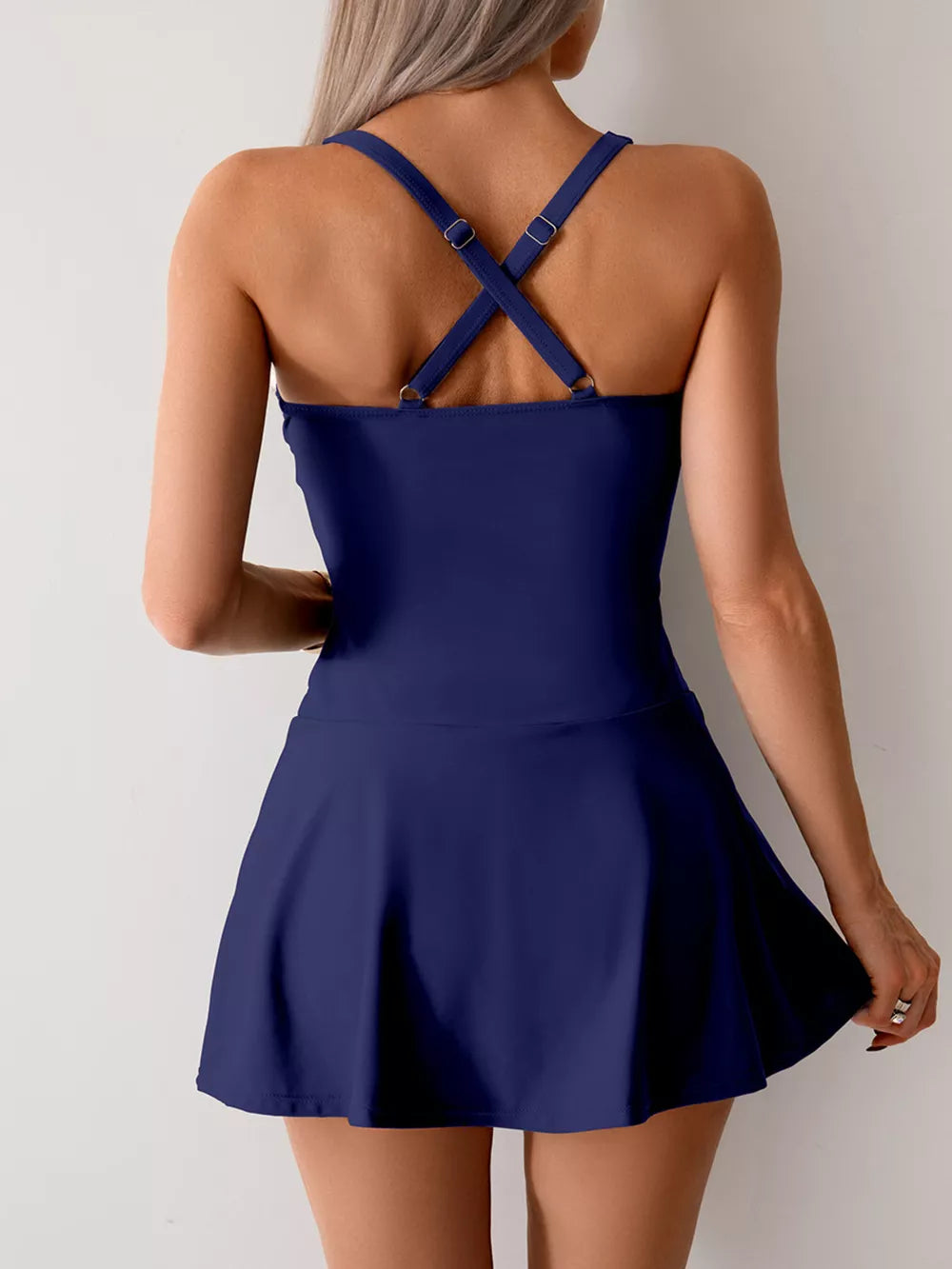 Navy blue one-piece swimsuit with crisscross back straps and a skirted bottom.