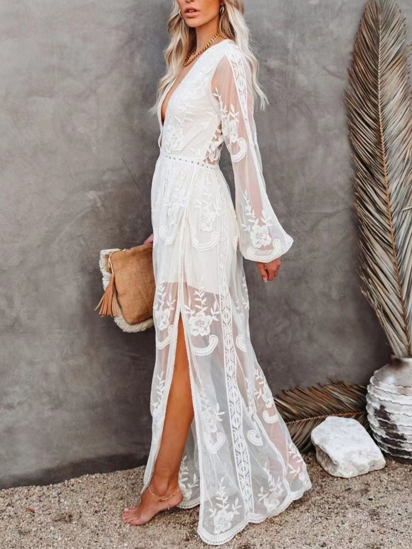 White floral lace maxi dress with plunging neckline, long bell sleeves, and high slit.