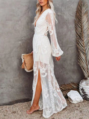 White floral lace maxi dress with plunging neckline, long bell sleeves, and high slit.