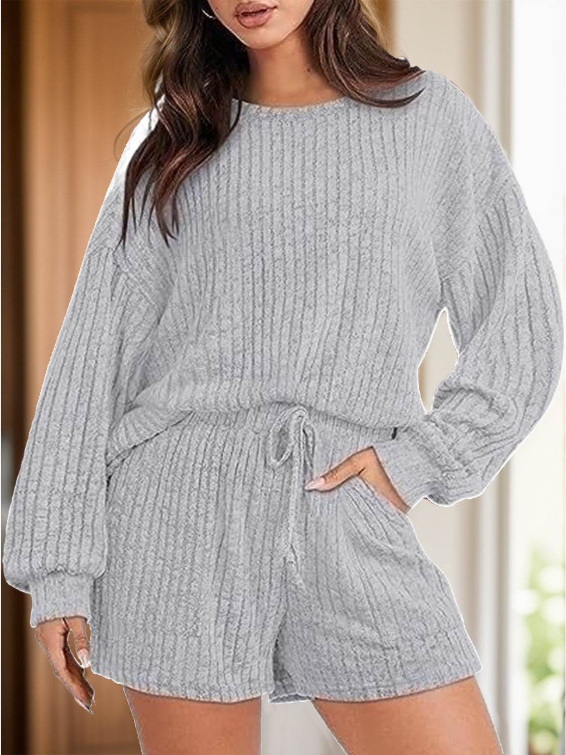 Light gray ribbed knit lounge set with crew neck top, long sleeves, and shorts with pockets and drawstring waist.