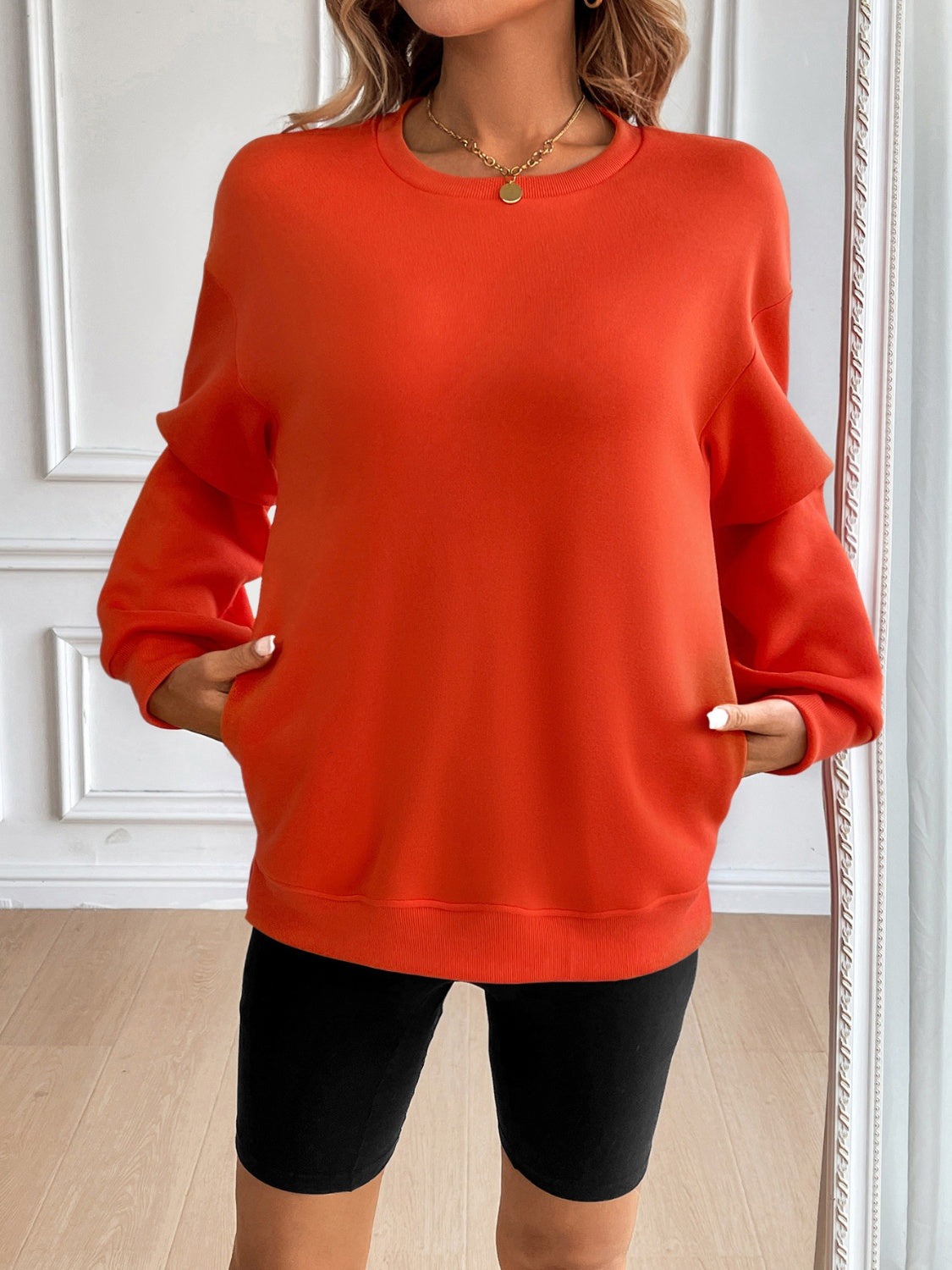 Orange relaxed fit sweatshirt with crewneck, long sleeves, and front pockets.