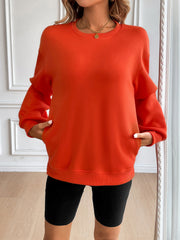 Orange relaxed fit sweatshirt with crewneck, long sleeves, and front pockets.