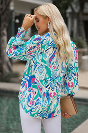 Abstract print blouse with gathered cuffs in blue, pink, and green.