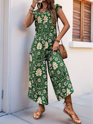 Botanical print culotte jumpsuit in dark green with cap sleeves and a round neckline.