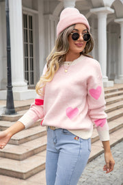 Blush pink intarsia knit crewneck sweater with heart pattern and cream trim.