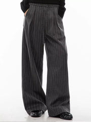 Men's dark grey pinstripe wide-leg pleated trousers with drawstring detail.