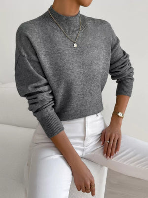 Gray mock neck knit sweater with dropped shoulders and ribbed cuffs.