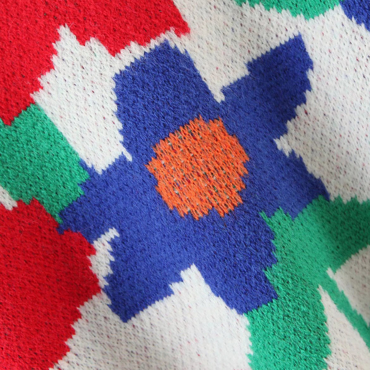 Floral intarsia knit sweater in white with blue, orange, red, and green geometric floral pattern.