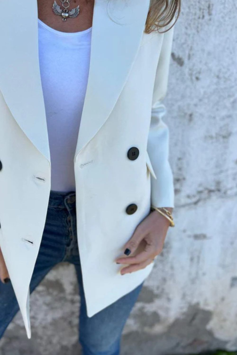 Ivory double-breasted blazer with sculpted lapels and dark buttons, styled with jeans.