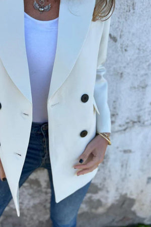 Ivory double-breasted blazer with sculpted lapels and dark buttons, styled with jeans.