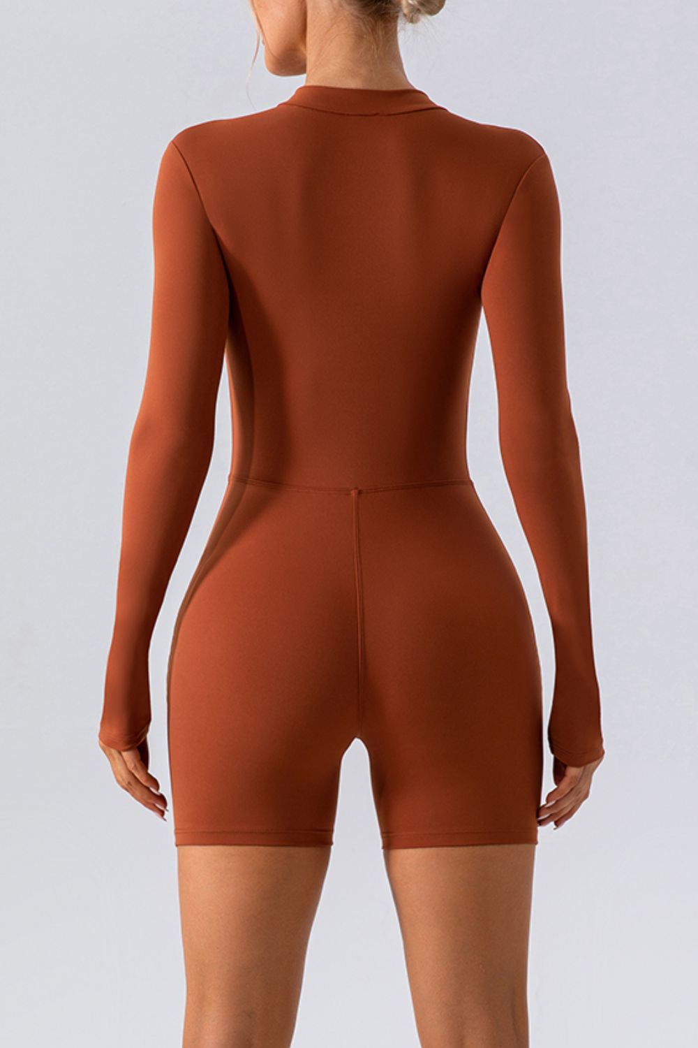 Sculpted performance romper in caramel with zip detail, long sleeves and short legs.