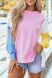 Colorblock sweatshirt in blush pink with blue, white, and yellow sleeves and split hem.