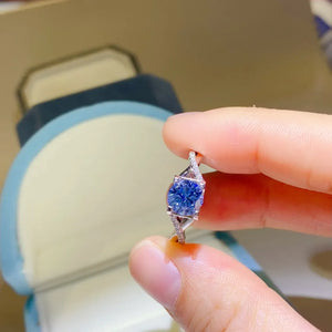 Silver twisted pavé moissanite engagement ring with a bright blue center stone.