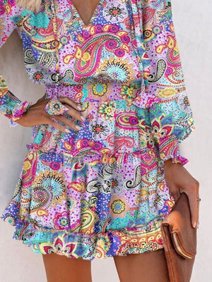 Abstract tiered dress with ruffles and paisley print in vibrant colors.