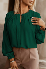 Green pleated yoke blouse with button detail and gathered cuffs.