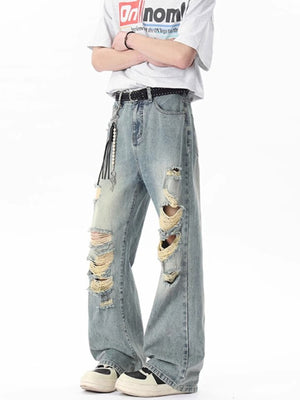 Men's light blue distressed wide-leg jeans with frayed details and a pearl chain accessory.