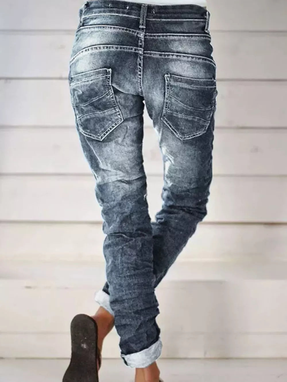 Dark blue cuffed button-fly jeans with distressed detailing and a relaxed fit.