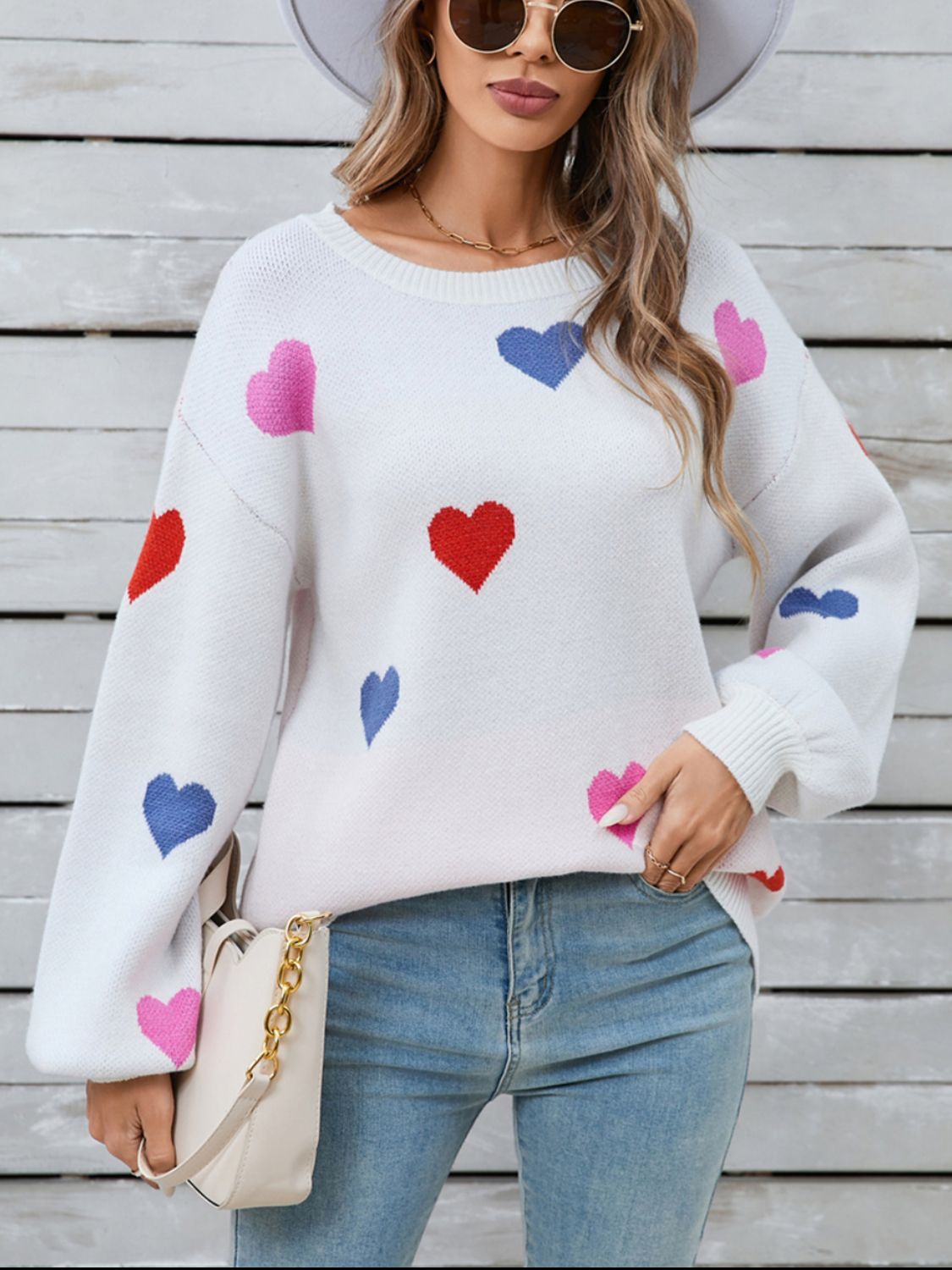 White knit sweater with bubble sleeves and a scattered heart motif in pink, red, and blue.