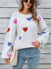 White knit sweater with bubble sleeves and a scattered heart motif in pink, red, and blue.