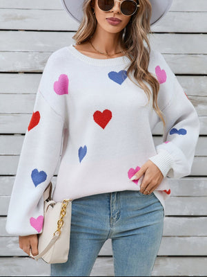 White knit sweater with bubble sleeves and a scattered heart motif in pink, red, and blue.