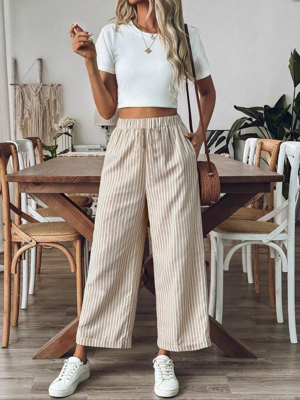 Chic high-waisted striped wide-leg pants in beige and white, cuffed hem, styled with a crop top and sneakers.