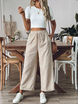 Chic high-waisted striped wide-leg pants in beige and white, cuffed hem, styled with a crop top and sneakers.