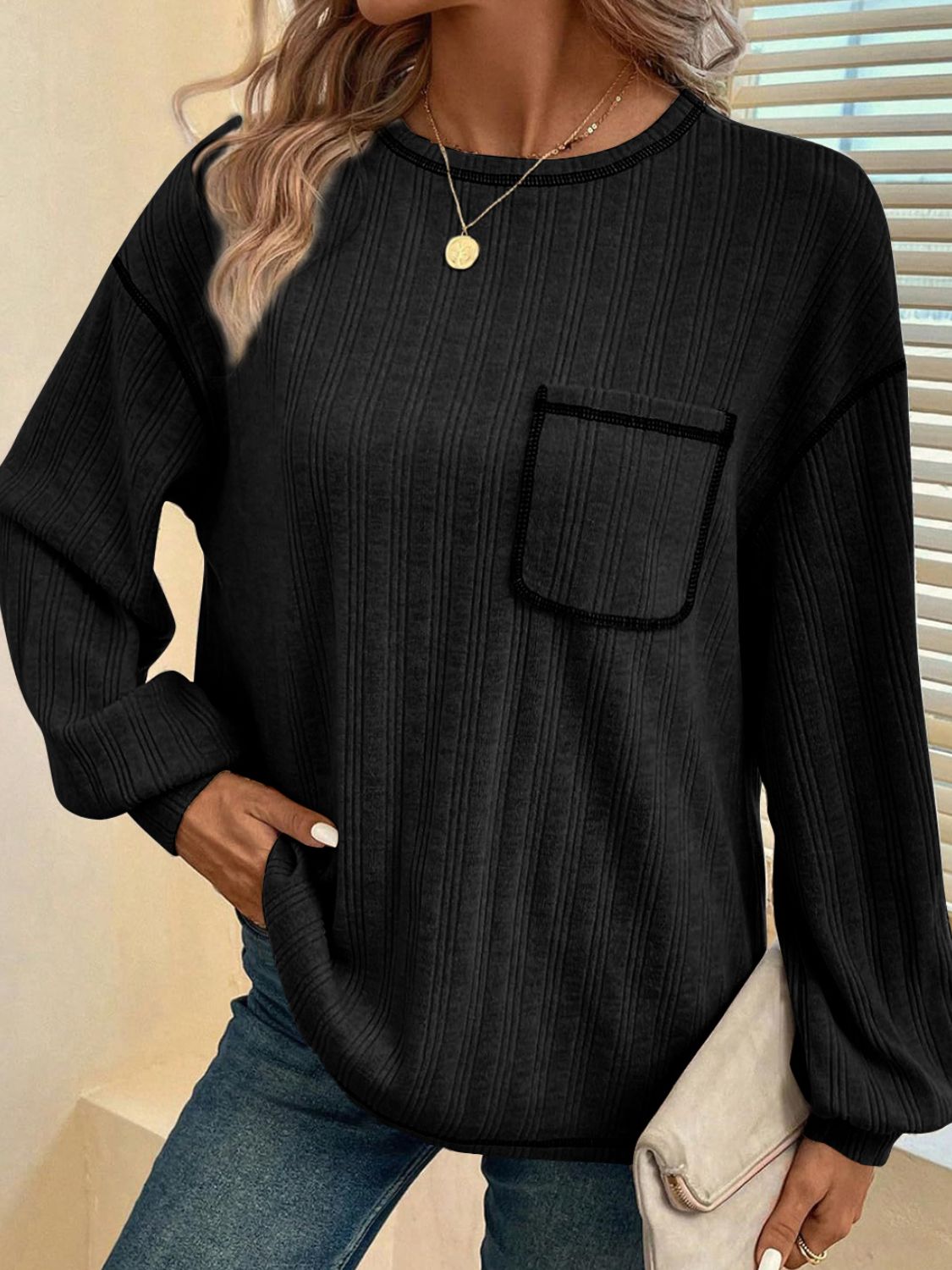 Black ribbed knit sweater with contrast stitch pocket and crew neck.
